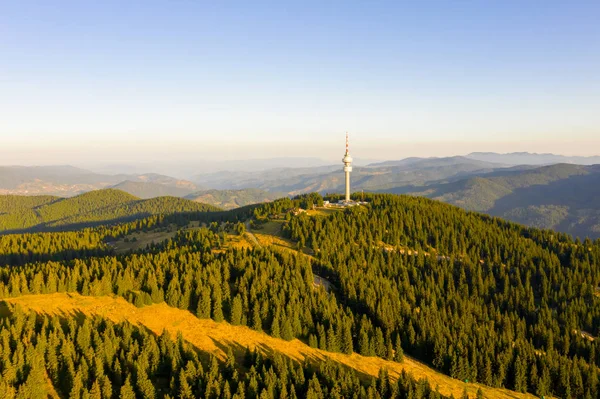 Αεροφωτογραφία του τηλεκατευθυνόμενου πύργου τηλεόρασης με ομίχλη στο βουνό την ηλιόλουστη μέρα — Φωτογραφία Αρχείου
