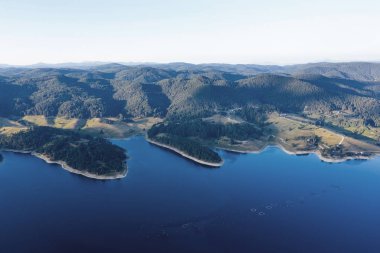 Bulgaristan 'da batan güneşin renkli ışınlarıyla çevrili göl ve dağlar. Balık çiftlikleri alabalığı ve göldeki diğer balıklar. İnsansız hava aracı ile hava görüntüsü