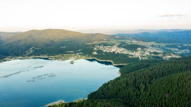 Bulgaristan 'da batan güneşin renkli ışınlarıyla çevrili göl ve dağlar. Balık çiftlikleri alabalığı ve göldeki diğer balıklar. İnsansız hava aracı ile hava görüntüsü