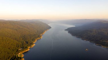 Bulgaristan 'da batan güneşin renkli ışınlarıyla çevrili göl ve dağlar. Balık çiftlikleri alabalığı ve göldeki diğer balıklar. İnsansız hava aracı ile hava görüntüsü