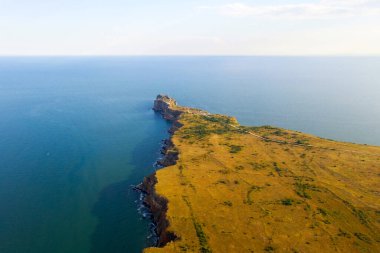 Kaliakra 'nın dar ve uzun burnu Bulgaristan' ın kuzey kıyısında denize açılıyor. Kırmızımsı bir rengin yüksek dik kıyıları çimlerin yeşilliği ve sonsuz mavi denizle uyum içindedir. İnsansız hava aracından görüntüle.