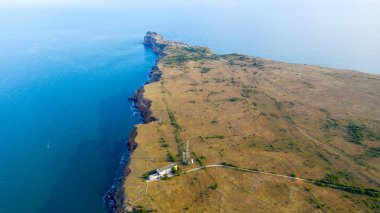 Kaliakra 'nın dar ve uzun burnu Bulgaristan' ın kuzey kıyısında denize açılıyor. Kırmızımsı bir rengin yüksek dik kıyıları çimlerin yeşilliği ve sonsuz mavi denizle uyum içindedir. İnsansız hava aracından görüntüle.