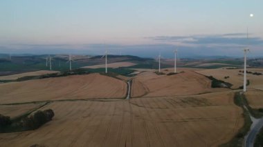 Highland 'da günbatımı gökyüzünde enerji üretimi için yel değirmenlerinin hava manzarası. Rüzgar güç türbinleri yenilenebilir temiz enerji üretiyor 