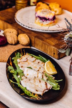 Ev mutfağında beyaz tabakta kızarmış kalamar. Mutfaktaki ahşap güvertede kızarmış kalamar..