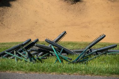 Golf sahasındaki bir sığınağa konmayı bekleyen kum süpürgeleri.