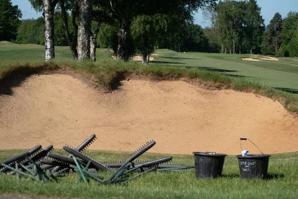 Golf sahasındaki bir sığınağa konmayı bekleyen kum süpürgeleri.