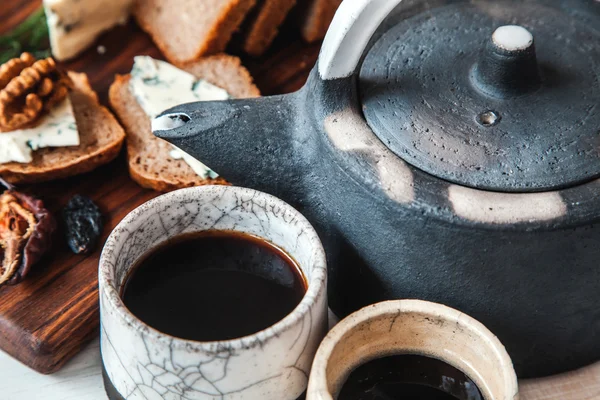 Waterkoker met twee kopjes thee en broodjes — Stockfoto