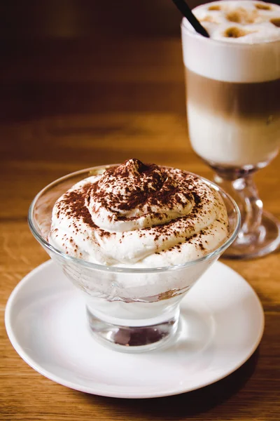 Tiramisu in a glass cup together with cappuccino coffee on table in restaurant — Stockfoto