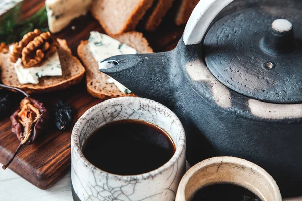 Oude keramische theepot met een kopje thee en koekjes in een kom op houten achtergrond — Stockfoto