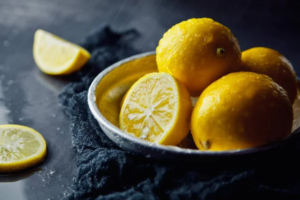 Hermosos limones maduros en plato sobre un fondo negro — Foto de Stock