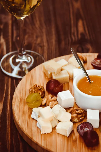 奶酪板配葡萄、 坚果、 木制背景上的白色酒一杯 — 图库照片