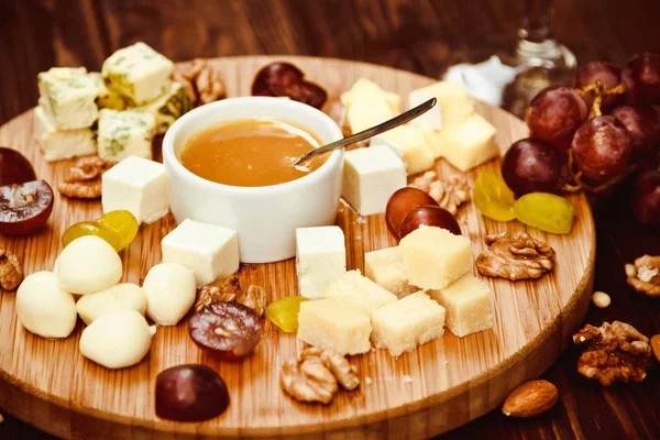 Cheese Board served with grapes and nuts on a wooden background — Stock Photo, Image