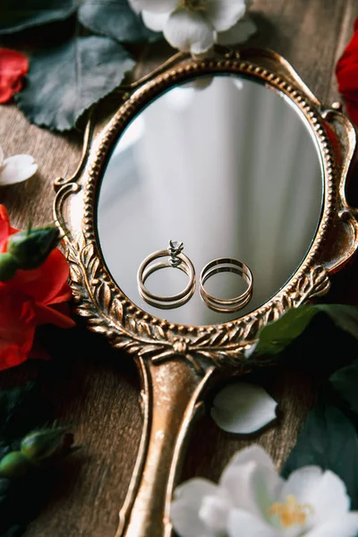 Hermosos anillos de boda en un espejo vintage con flores — Foto de Stock