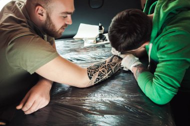 Ana dövme sanatçısı eldiven yandan erkek dövme yapar