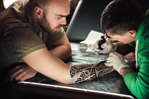 Maestru artist tatuaj în mănuși face tatuaj pe bărbați de mână — Fotografie, imagine de stoc