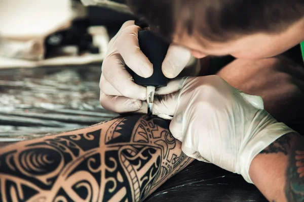 Mestre tatuador em luvas faz tatuagem na mão homens — Fotografia de Stock