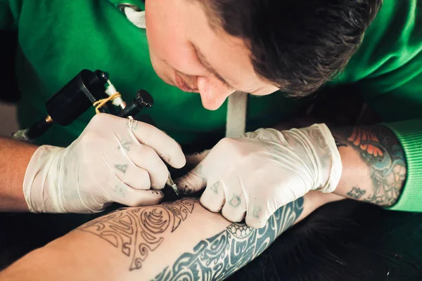 Mestre tatuador em luvas faz tatuagem na mão homens — Fotografia de Stock