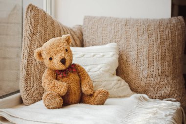 A beautiful soft toy bear sits on the bed  clipart