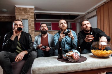 Evde kanepede oturmuş sakallı erkekler