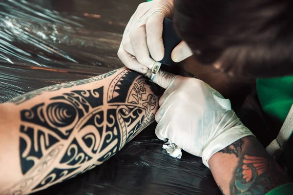 Maestro tatuatore in guanti fa tatuaggio su uomini mano — Foto Stock