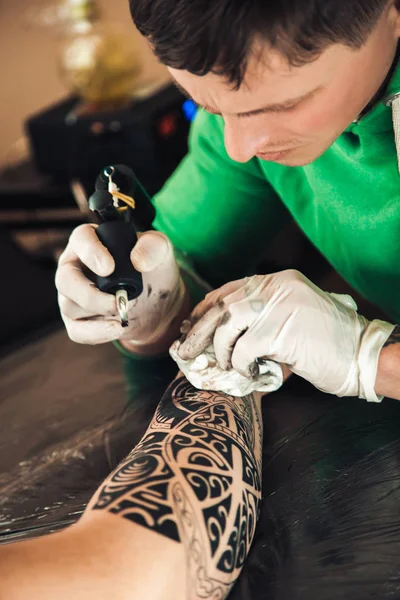 Master tatuerare i handskar gör tatuering å män — Stockfoto