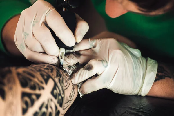 Майстер татуювання художника в рукавичках робить татуювання на руках чоловіків — стокове фото