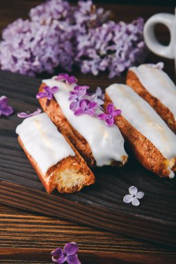 Güzel pasta kek krem ve eflatun çiçekli ahşap tahta üzerinde çay ile