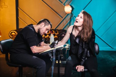 Ana dövmeci dövme el istemci kız bir atölyede özel ekipman ile cilt üzerinde yapar