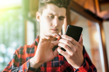 Bir akıllı telefon elinde tutan ve gözü üstünde ciddi bir ifade ile şık yakışıklı genç adam. İletişim, yazışma ve çağdaş eserler kavramı