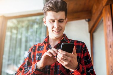 Bir akıllı telefon elinde tutan ve gözü üstünde şık yakışıklı genç adam