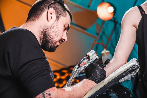 Mestre tatuador faz uma tatuagem na pele da mão cliente menina em uma oficina com equipamento especial — Fotografia de Stock