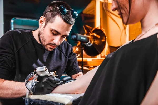 Mester tattooist tesz egy tetoválás a bőr a kéz ügyfél lány egy workshop, speciális felszerelés — Stock Fotó