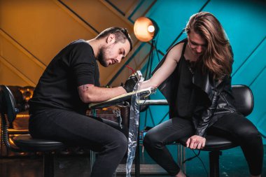 Ana dövmeci dövme el istemci kız bir atölyede özel ekipman ile cilt üzerinde yapar