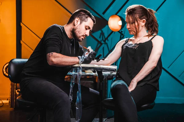 Master tattooist makes a tattoo on the skin of the hand client girl in a workshop with special equipment — Stock Photo, Image