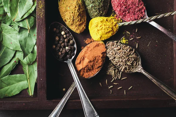 İçinde karanlık bir arka plan üzerinde varlıklı bir güzel renkli baharatlar. Yemek, sağlıklı gıda kavramı