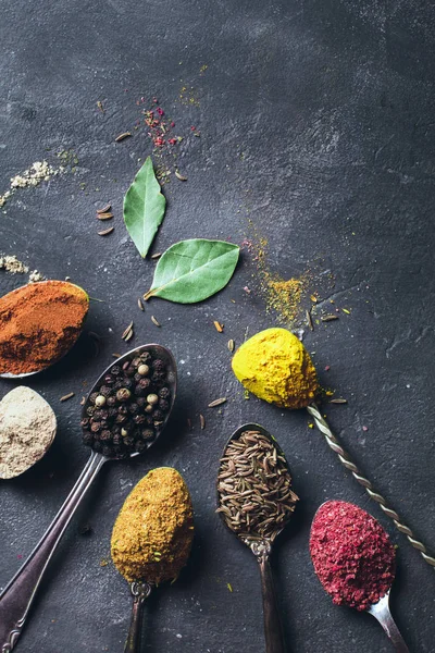 Belas especiarias coloridas em uma colher de prata em um fundo escuro. O conceito de cozinhar, comida saudável — Fotografia de Stock