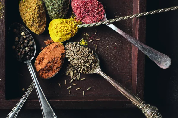 Hermosas especias de colores en una cuchara de plata sobre un fondo oscuro. El concepto de cocina, comida saludable —  Fotos de Stock