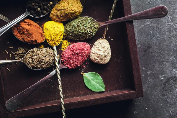 Beautiful colored spices in a silver spoon on a dark background. The concept of cooking, healthy food — Stock Photo, Image