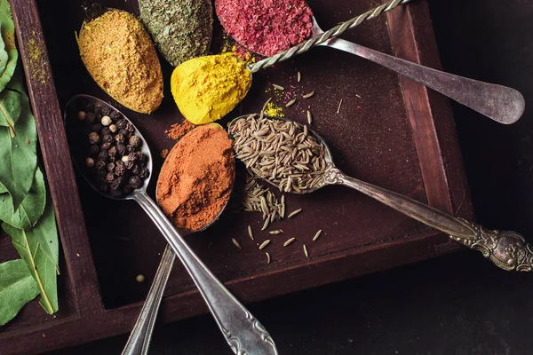 İçinde karanlık bir arka plan üzerinde varlıklı bir güzel renkli baharatlar. Yemek, sağlıklı gıda kavramı