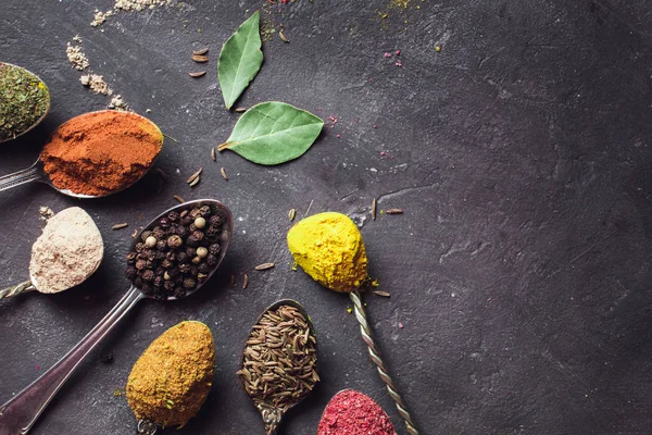 Hermosas especias de colores en una cuchara de plata sobre un fondo oscuro. El concepto de cocina, comida saludable — Foto de Stock