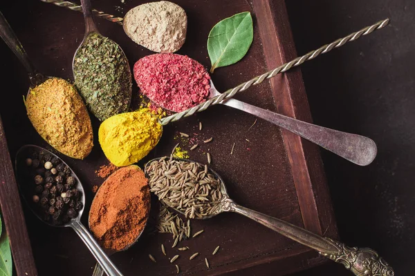 Hermosas especias de colores en una cuchara de plata sobre un fondo oscuro. El concepto de cocina, comida saludable —  Fotos de Stock