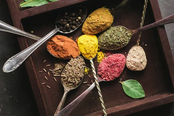 Beautiful colored spices in a silver spoon on a dark background. The concept of cooking, healthy food — Stock Photo, Image