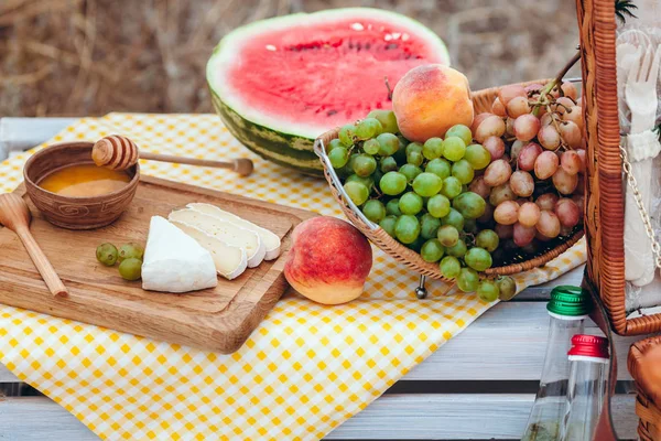 Ensemble de pique-nique avec fruits, fromage, pain grillé, miel, vin avec un panier en osier sur couvre-lit. Beau fond d'été avec nourriture et boisson sur la nature — Photo