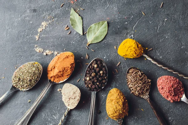 Beautiful colored spices in a silver spoon on a dark background. The concept of cooking, healthy food — Stock Photo, Image