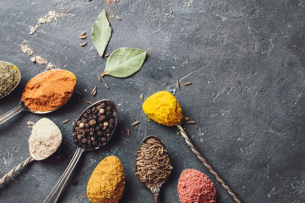 Belas especiarias coloridas em uma colher de prata em um fundo escuro. O conceito de cozinhar, comida saudável — Fotografia de Stock