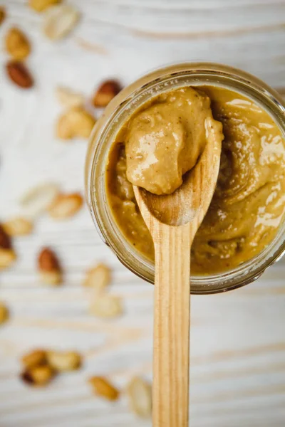 Glas Und Löffel Erdnussbutter Und Erdnüsse Auf Holzgrund Von Oben lizenzfreie Stockfotos