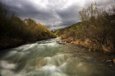 Bulutlu bir gökyüzünün altındaki vahşi nehir İspanyol Pireneleri 'nde uzun pozlama fotoğrafında