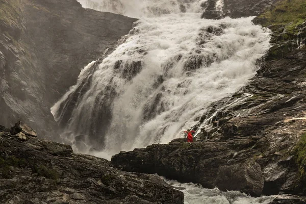 在挪威的岩石景观中 一名身穿红色连衣裙的女子在Kjosfossen瀑布边跳舞 — 图库照片