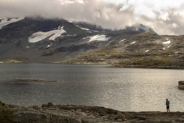 Karlı dağlar ve Norveç 'te 55. Yol' da bir göl içeren bir manzara.