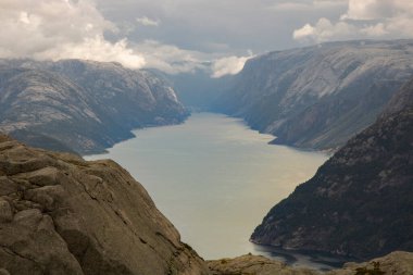 Lysefjord 'u ve etrafındaki dağları gösteren muhteşem bir manzara. Bulutlu bir gökyüzünün altında Preikestolen turist minber kayasına giden yürüyüş rotasında.